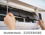 Small photo of Asian woman cleaning a dirty and dusty air conditioning filter in her house. Housewife removing a dusty air conditioner filter.