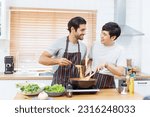 Small photo of LGBTQ+ gay bisexual cooking their meal together in the kitchen, LGBTQ gay couple making a spaghetti. A different ethnicity handsome gay couple enjoy cooking a spaghetti together in kitchen.
