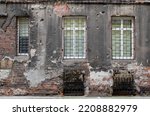 Small photo of Dilapidated emergency housing. The wall of an old house with a cracked facade and barred windows. Wall texture of a crumbling house