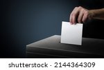 Dark side ballot box with hand person vote on blank voting slip at dark background.