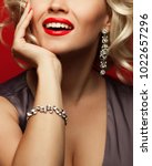 Small photo of Girl's best friends and femme fatale concept. Marilyn Monroe style. Close up portrait of rich woman smiling wearing expensive luxurious diamond bracelet, earring. Studio shot