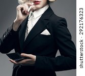 Small photo of Femme fatale concept. Marlene Dietrich style. Close up retro portrait of rich young woman smiling wearing expensive luxurious tuxedo and smoking cigarette over gray background. Studio shot