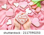 background banner greeting card for international women day with white heart love in woman hands, tulips and pigeon shape gingerbread cookies on silk fabric background