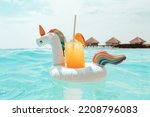 Small photo of served floating inflatable unicorn in ocean with cocktail drinks on tropical island resort in Maldives, honeymoon in luxury hotel, travel concept