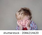Small photo of Young mischievoous boy grinning with an impish look on a textured wall background with copyspace