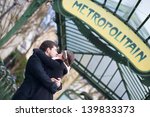 Couple kissing under the metro sign in Paris