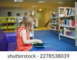 Preschooler 4 year old girl reading a book in municipal library