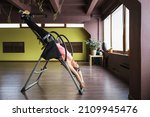 A woman doing inversion therapy hanging upside down on an inversion table, the therapy session is being done in a studio