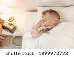Small photo of Sleeping man with chronic breathing issues considers using CPAP machine in bed. Healthcare, Obstructive sleep apnea therapy, CPAP, snoring concept
