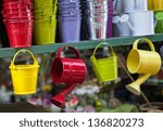 Colorful watering cans and buckets for plants at flower market in Paris.
