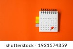 Small photo of red thumbtacks pointed at the end of month on white calendar with vivid grunge orange paper background , business or education concept