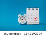 red thumbtack pin on the last day  of month with circle and pay day word near white analog clock on grunge blue background for business and finance concept