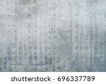 Smooth bare concrete wall with many concrete form dimples and grid lines.