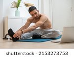 Young guy with average body type trying to improve his muscles, lose belly fat and lose weight on specific body parts while watching online workout courses and practicing on exercise mat at home.