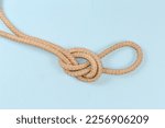 Rope knot Overhand loop, also known as loop knot tied with a climbing rope, close-up on a blue background