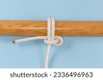 Small photo of Rope knot Pedigree cow hitch, version of the cow hitch, when only one rope is being pulled. Used to attach a rope to an object, view on a blue background