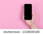 Top view of a woman hand using phone on pink pastel background.
