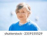 Outdoor portrait of beautiful 55 - 60 year old woman, wearing blue pullover