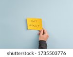 Male hand placing yellow post it paper with a Dont worry sign over light blue background.