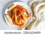 Steamed shrimps with herbs and sliced lemon on white plate. Seafood dish.