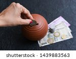 Small photo of Woman putting wages in coin stack jar saving money for her child. Kids piggy bank for savings cash deposit for future. 500 rupee banknote India. Profit from business. New Indian currency notes of 2000
