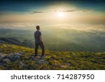 Man standing on a mountain hill and contemplate the sunset above Crimea mountains.