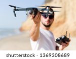 Young man holding drone before flight near ocean or sea. Pretty guy prepare to pilot outdoor