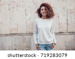 Curly haired girl with freckles in blank grey sweatshirt on the street. Mock up.