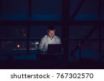 Businessman working on laptop in night office.