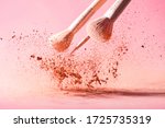 Make up brushes with powder splashes isolated on pink background