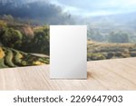 Small photo of Mock up Label the blank menu frame in Bar restaurant. Stand for booklet with white sheet paper acrylic tent card on table wiht blurred mountain background. Can inserting the text or picture.