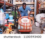 Small photo of Focused African American diligent positive cheerful carrying handbarrow with construction supplies purchased in shop of building materials