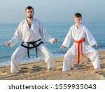 Small photo of Man and boy practicing karate at ocean quay