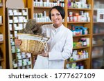 Small photo of Portrait of cheerful female pharmacist with dried vulnerary plans in hands