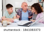 Small photo of Chagrined family with teenage son working with papers at home