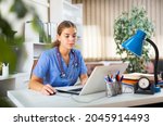 Young woman doctor is working at a computer, sitting at workplace in the resident