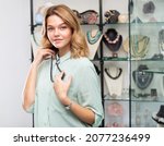 Small photo of Portrait of happy young woman choosing black nacreous stone bead necklace in shop
