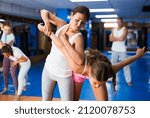 Asian woman exercising armlock movement during self-defence class.