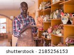 Small photo of Professional confident African American potter proffering goods in pottery shop
