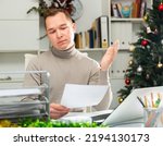 Portrait of disappointed man sitting at table in office. Frustrated manager doing paperwork in Christmas decorated office.