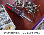 Set of crosshead screwdriver with tip set and fastening devices on wooden background