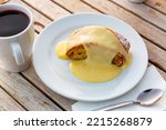 Apple strudel biscuit on the white ceramic plate with cup of hot wine on a wooden table in a cafe