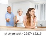 Small photo of Upset adult daughter happens to reproach parents in the kitchen