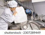 Small photo of Woman brewer in white coat pouring beer yeast into tank in beer factory.
