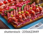 Small photo of Slices of Spanish dry-cured gammon, variety of sausages and bacon on wooden board garnished with vegetables