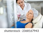 Small photo of Beautiful female doctor making facial gas-liquid oxygen water epidermal peeling using macromolecule atomizing pen for adult woman at modern beauty salon. Skin care concept. Beauty treatment