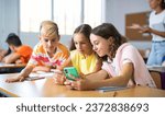 Small photo of Group of kids using smartphones during lesson in school. Girls and boys using gadgets while studying.