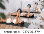 Teenage girl doing pilates exercises with soft ball in female group in studio