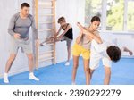 Small photo of Boys and girls train technique of performing protection with wring hands during training in self-defense techniques. Teenagers prepare for competition, under guidance of coach repeat combat skills