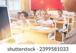 Small photo of Portrait of diligent towheaded preteen girl looking at camera during lesson in primary school